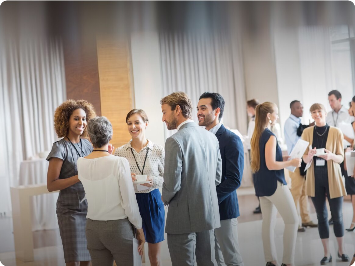 A Group of Business Employees Smiling and Talking to Suppliers After a Convention
