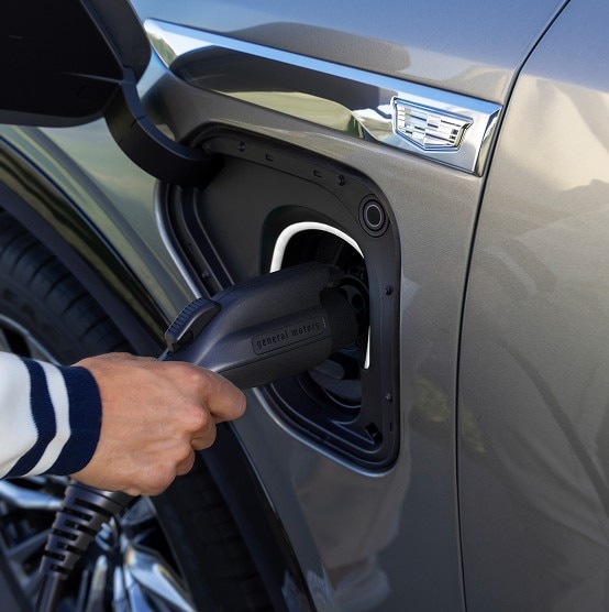 Close-up of a Cadillac VISTIQ being charged using a General Motors EV charger, highlighting electric charging capability.