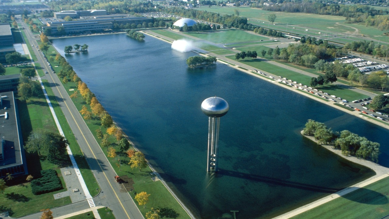 Aerial view of the General Motors Technical Center, featuring a water tower, large reflecting pool, and modernist buildings.